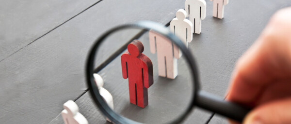 Magnifier on the one wooden red person between other people
