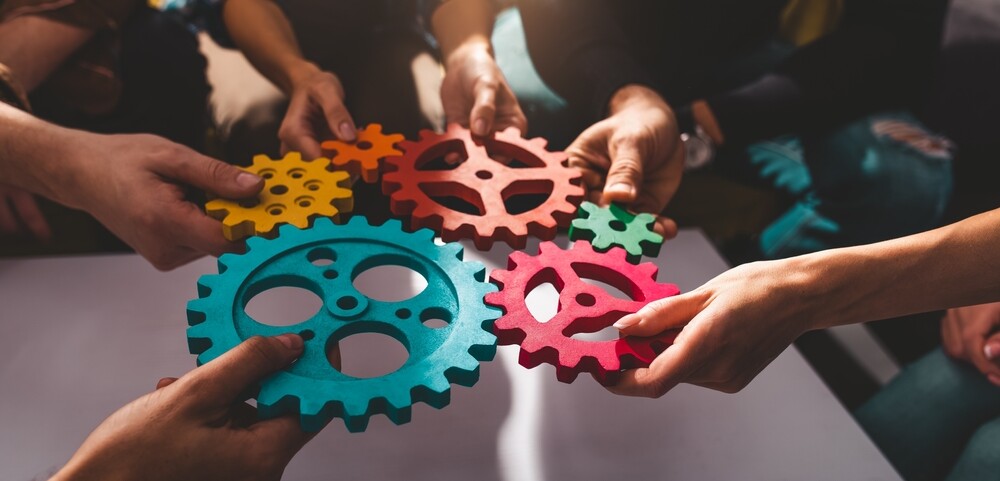Team of people work together and combine pieces of gears