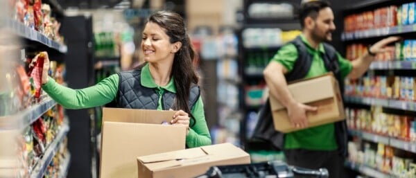 Retail employees putting products on shelves in supermarket
