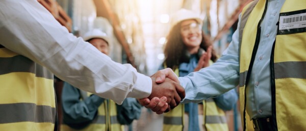 Warehouse, shipping deal and people with handshake for agreement, applause or partnership. Logistics team, collaboration or workers shaking hands for supply chain, distribution or thank you for stock