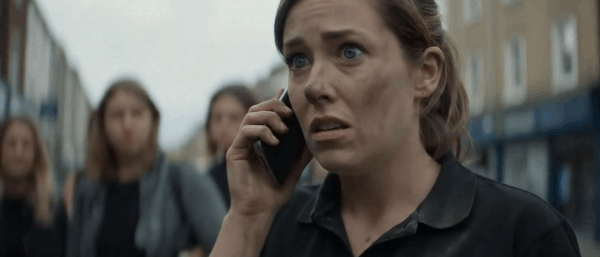 Image of woman, retail worker, outside helping customers evacuate. She's on the phone. Emergency