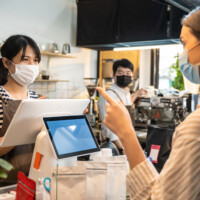 customer ordering takeaway food with waiter worker at cafe. Business owner barista woman in apron wear mask due to Covid19 pandemic, work in restaurant serve occupation service young girl.